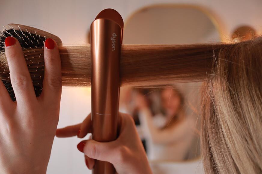 Волосы выпрямляются с помощью утюжка Dyson Corrale. 